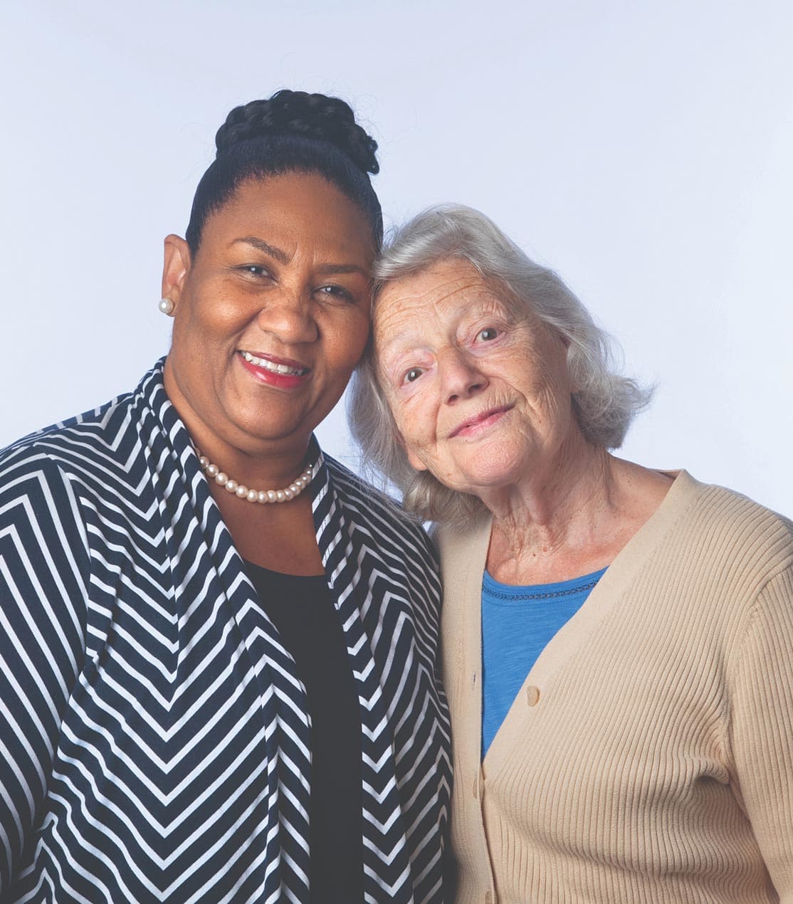 Two elderly friends, one Black and one white, embracing warmly.